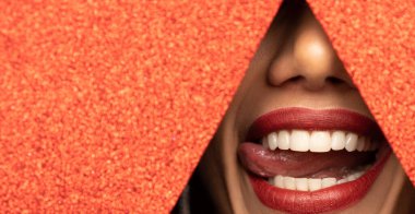 Kırmızı dudaklar parlak kırmızı bir kağıttaki delikten süzülüyor. Güzel beyaz dişler.