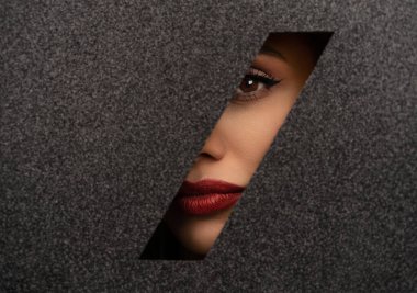 Kırmızı dudaklar, parlak siyah bir kağıttaki delikten süzülüyor..