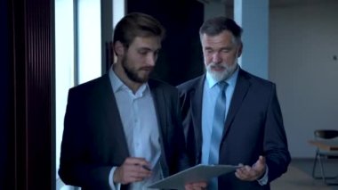 İş adamları modern ofis lobisinde toplanıyor, yürüyor ve konuşuyorlar..