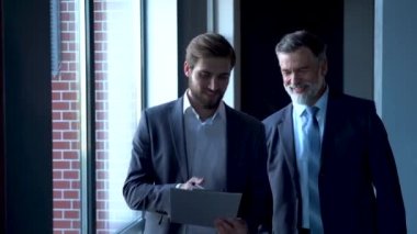 İş adamları modern ofis lobisinde toplanıyor, yürüyor ve konuşuyorlar..