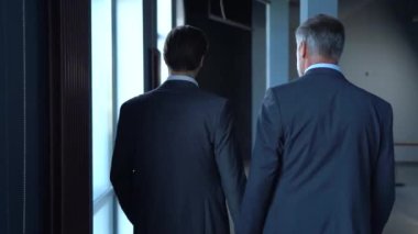 İşletme yöneticilerinin modern ofis lobisinde buluşması, yürümesi ve konuşması..