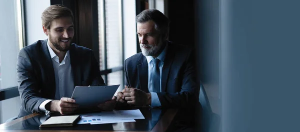 Empresário sênior e júnior discutir algo durante a reunião, fundo do escritório . — Fotografia de Stock