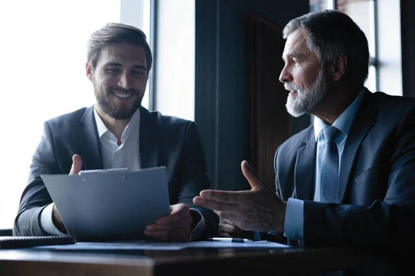 Senior en junior zakenman iets bespreken tijdens hun bijeenkomst, office achtergrond. — Stockfoto