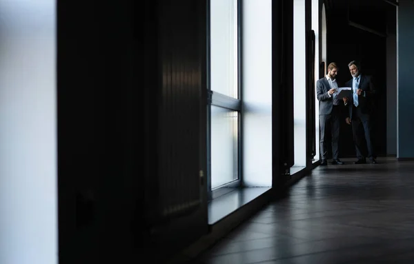 Two colleagues communicating in corridor, partners walking in the modern office — Stock Photo, Image