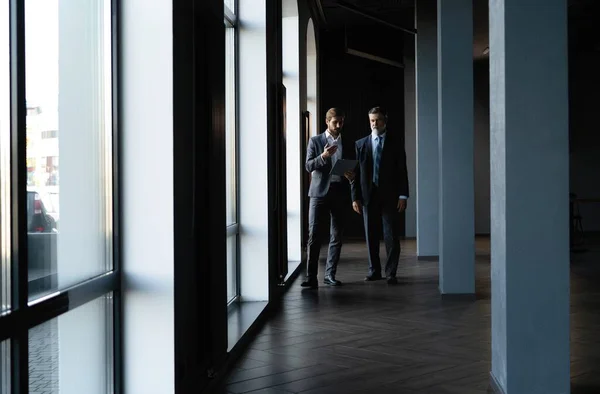 Two colleagues communicating in corridor, partners walking in the modern office — Stock Photo, Image