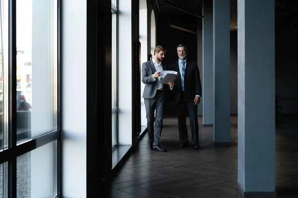 Two colleagues communicating in corridor, partners walking in the modern office — Stock Photo, Image