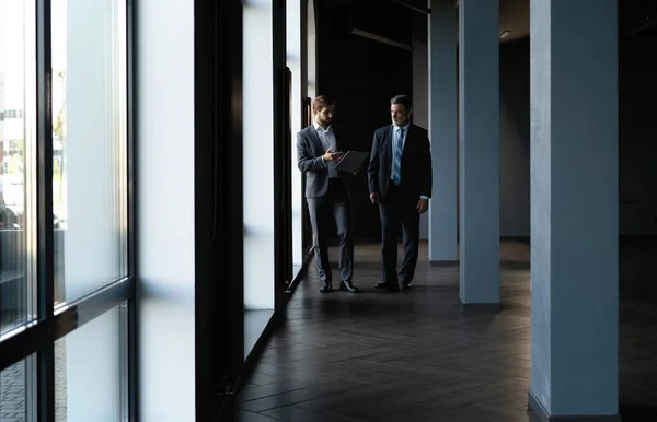 Two colleagues communicating in corridor, partners walking in the modern office — Stock Photo, Image