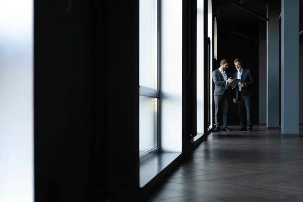 Dwóch kolegów komunikujących się w korytarzu, partnerzy spacerujący w nowoczesnym biurze Obrazek Stockowy