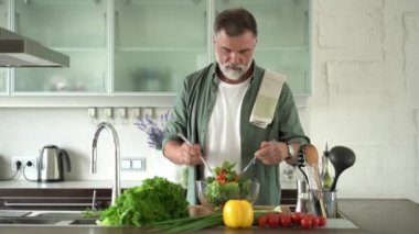 Yakışıklı Olgun Adam sebzelerin üzerine zeytinyağı serpiyor Taze salata
