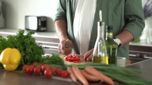Volwassen gelukkige man die thuis gezond eten bereidt, verse groentesalade snijdt in een modern keukeninterieur. — Stockvideo