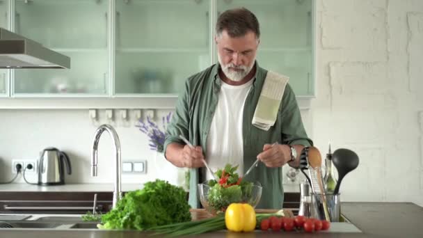 Bonito homem maduro polvilhe com azeite sobre legumes salada fresca — Vídeo de Stock