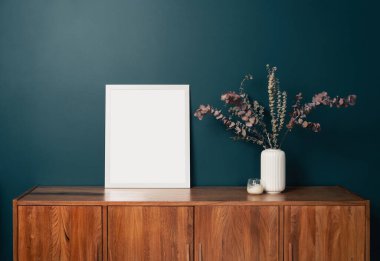 Yeşil duvardaki boş resim çerçevesi modeli. Zümrüt oturma odası tasarımı. Modern İskandinav tarzı iç mekan manzarası ve sanat eserleri duvarda. Ev sahneleme ve minimalizm kavramı