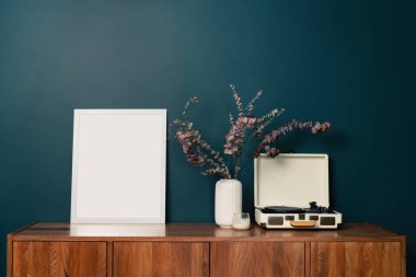 Yeşil duvardaki boş resim çerçevesi modeli. Zümrüt oturma odası tasarımı. Modern İskandinav tarzı iç mekan manzarası ve sanat eserleri duvarda. Ev sahneleme ve minimalizm kavramı