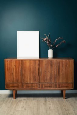 Yeşil duvardaki boş resim çerçevesi modeli. Zümrüt oturma odası tasarımı. Modern İskandinav tarzı iç mekan manzarası ve sanat eserleri duvarda. Ev sahneleme ve minimalizm kavramı