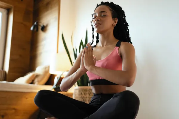 Genç siyahi kadın evde yoga yapıyor. Lotus pozisyonunda.. — Stok fotoğraf
