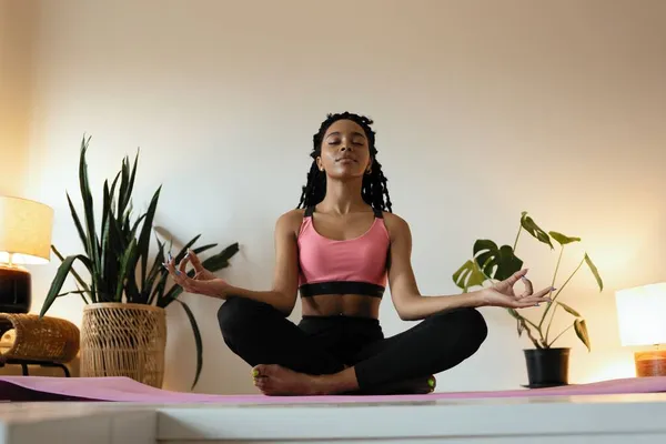 Jovem mulher negra fazendo ioga em casa na posição de lótus. — Fotografia de Stock