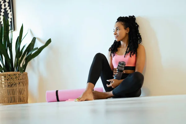 Zadowolona młoda czarna kobieta siedzi i relaksuje się po pracy — Zdjęcie stockowe