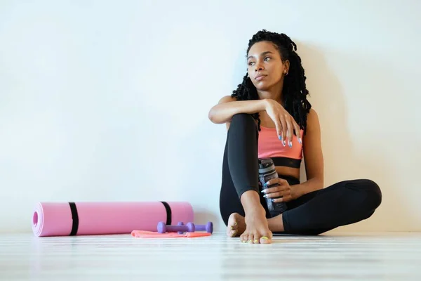 Satisfecho joven mujer negra sentado y relajante después de su entrenamiento — Foto de Stock