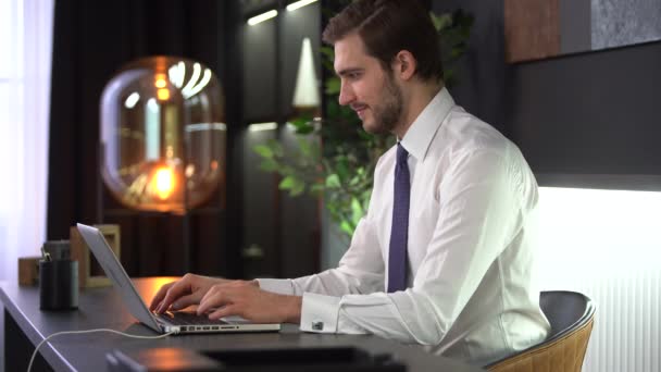 Εστιασμένος επιχειρηματίας δακτυλογραφεί σε φορητό υπολογιστή κάνει έρευνα. Νεαρός επαγγελματίας που χρησιμοποιεί υπολογιστή κάθεται στο γραφείο — Αρχείο Βίντεο