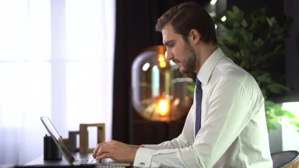 Homem de negócios focado digitando no laptop fazendo pesquisa. Jovem profissional masculino usando computador sentado na mesa de escritório — Vídeo de Stock