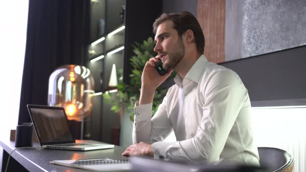 Sorridente giovane uomo d'affari professionista adulto che fa chiamate d'affari parlando sullo smartphone in ufficio — Video Stock