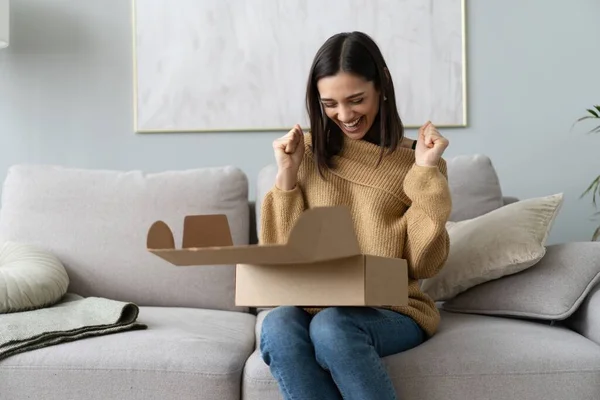 Glückliche junge Frau sitzt auf Couch Zimmer auspacken Pappkartons Waren im Internet kaufen. Online einkaufen, Lieferkonzept — Stockfoto