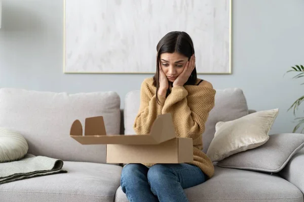 Arrabbiato confuso donna disimballaggio pacco, sbagliato o rotto ordine negozio online. Cattivo servizio di consegna Fotografia Stock