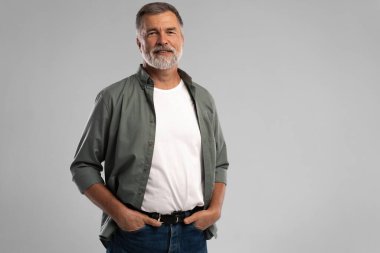 Beyaz arka planda duran gülümseyen olgun bir adamın portresi.