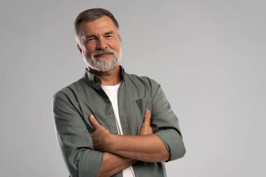 Beyaz arka planda duran gülümseyen olgun bir adamın portresi.