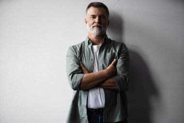 Beyaz arka planda duran gülümseyen olgun bir adamın portresi.