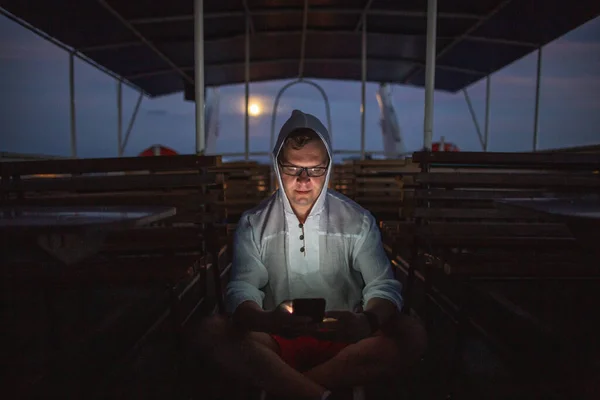 Драматичний нічний портрет чоловіка з телефоном на порожньому кораблі задоволення — стокове фото