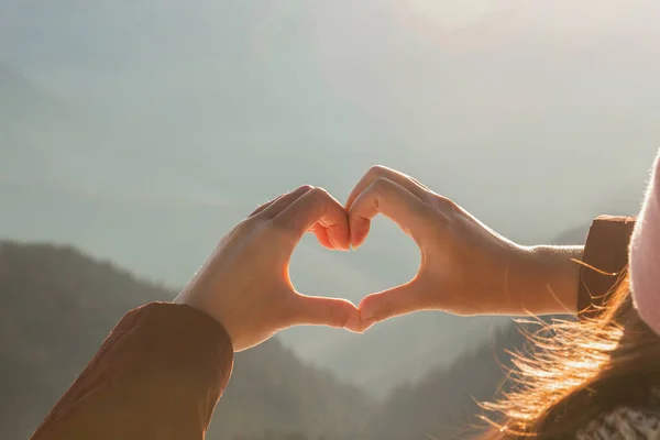 Frau, die an einem sonnigen Wintertag mit den Händen Herzform über schneebedeckten Bergen herstellt. Valentinstag-Konzept — Stockfoto