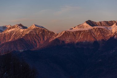 Gün batımından sonra hassas pastel mor tonlarda kar kaplı dağların manzarası