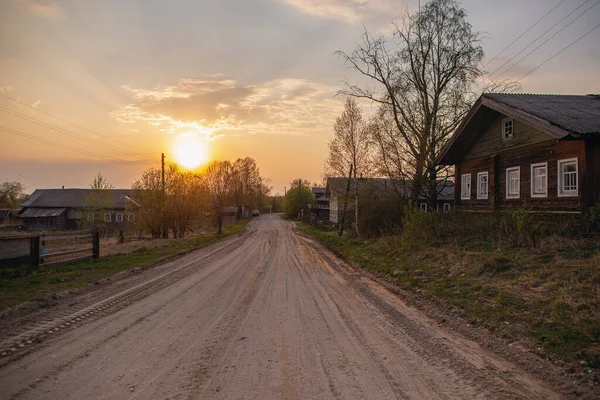 Carro andando em uma estrada de cascalho de terra com em um pôr do sol de primavera. Vila russa — Fotografia de Stock