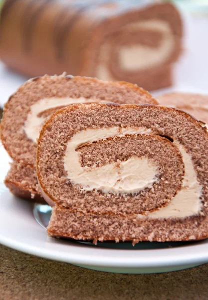 Rolo de esponja suíço com creme na placa branca — Fotografia de Stock