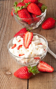 kwark en aardbeien in witte kom op houten oppervlak.