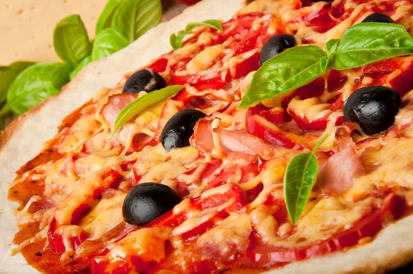Крупный план пиццы с помидорами, сыром, черными оливками и перцем — стоковое фото