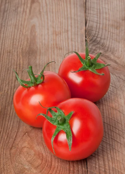 Tomates frescos y maduros sobre una vieja tabla de madera — Foto de Stock