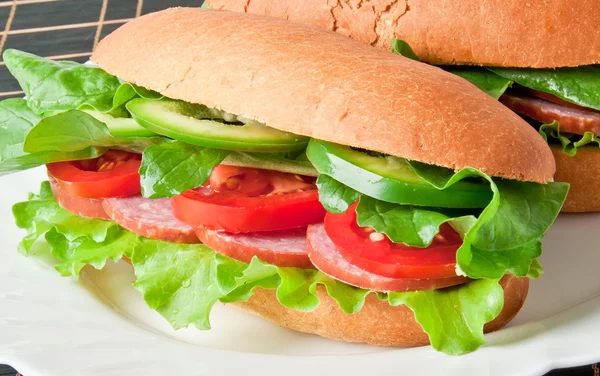 Sanduíche com presunto, tomate, pepino e rúcula na placa branca — Fotografia de Stock