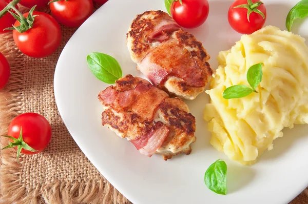 Grilled chicken patties wrapped strips of bacon and mashed potatoes — Stock Photo, Image