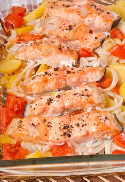 Trozos de salmón con patatas, tomates y cebollas al horno — Foto de Stock