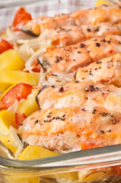 Stukken van zalm met aardappelen, tomaten en uien gebakken in de oven — Stockfoto