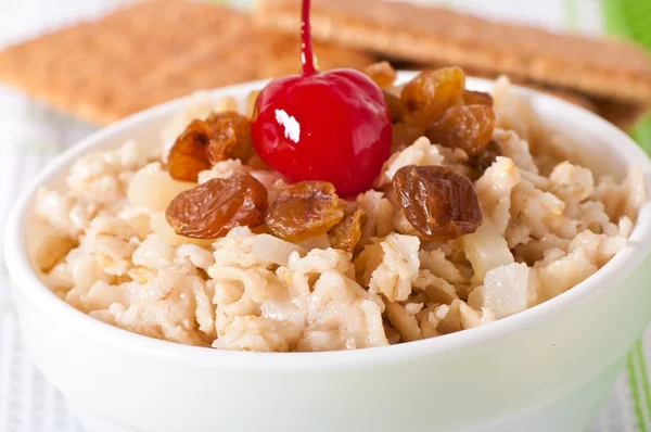 Oatmeal with raisins and cherries in a white bowl — Stock Photo, Image