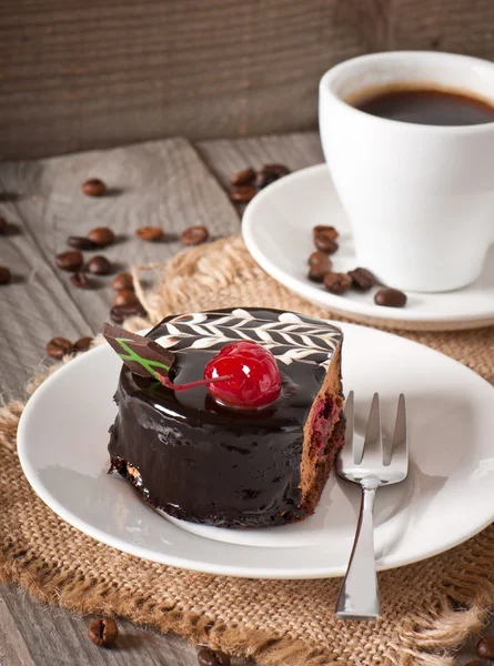 Sweet dessert fruitcake with a cherry and a cup of coffee — Stock Photo, Image