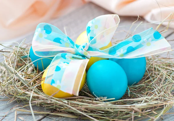 Easter eggs in nest on wooden background — Stock Photo, Image