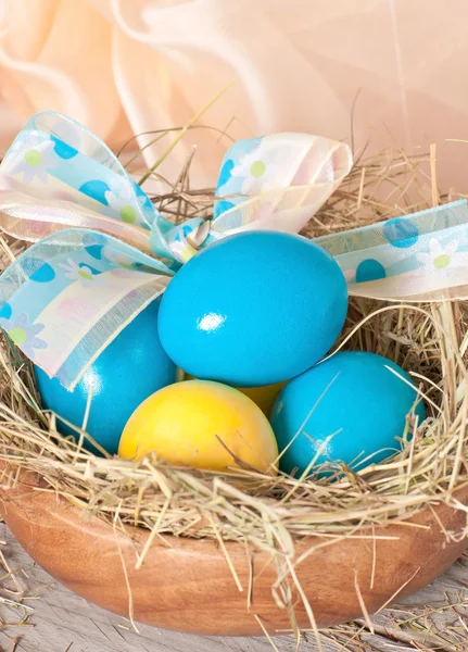 Easter eggs in nest on wooden background — Stock Photo, Image