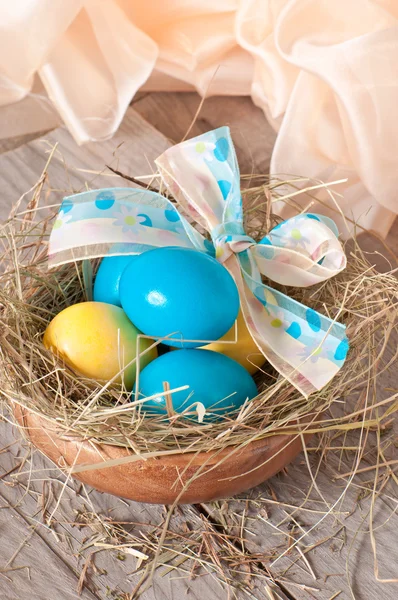 Easter eggs in nest on wooden background — Stock Photo, Image