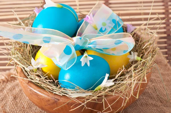 Easter eggs in nest on wooden background — Stock Photo, Image