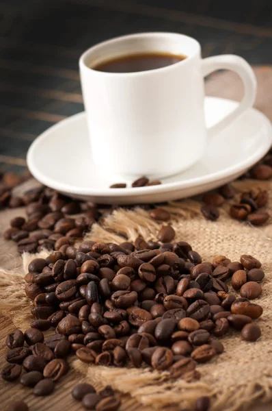 Closeup view of a cup of coffee and coffee beans — Stock Photo, Image