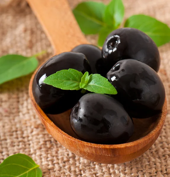 Черные оливки на деревянном столе — стоковое фото